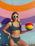 Two-piece high-waisted bikini set featuring an all-over print of blue skulls with purple bows and multicolored stars on a dark background. Includes a deep V-neck bikini top with wide straps and matching high-rise bottoms. Made from soft, stretchy fabric with a smooth black inner lining. The design combines bold, edgy graphics with a flattering retro-inspired silhouette.
